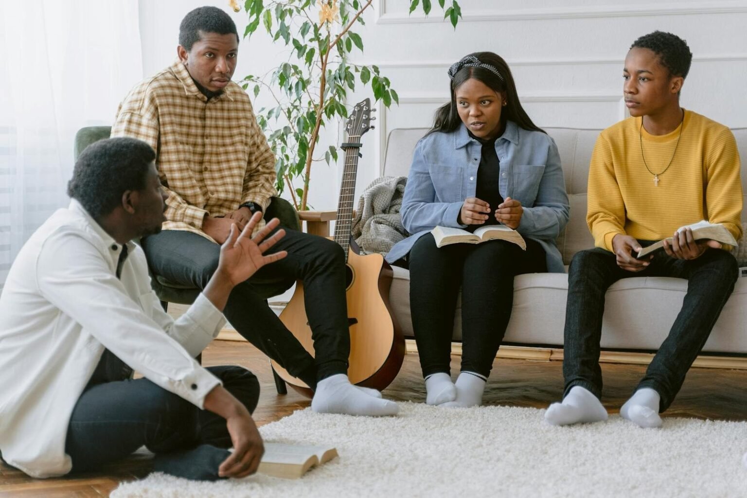 A group of four adults engaging in prayer and music indoors.